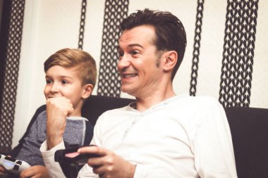 Happy man celebrating victory while playing video game with his son at home.