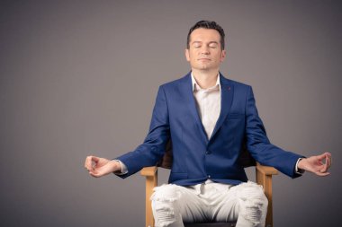 Businessman doing Yoga breathing exercise with eyes closed against the wall. 