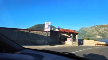 Kotor Körfezi 'nin kıyısı boyunca uzanan dolambaçlı bir yolda giderken, körfezin su yüzeyinin aynaya benzeyen muhteşem manzarası.