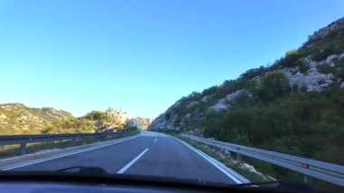 Kotor Körfezi 'nin kıyısı boyunca uzanan dolambaçlı bir yolda giderken, körfezin su yüzeyinin aynaya benzeyen muhteşem manzarası.