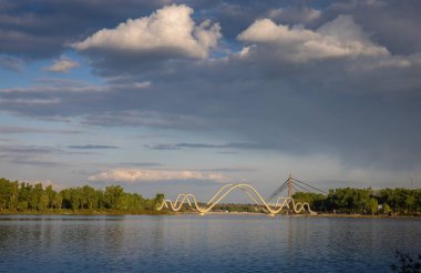 Ukrayna 'nın Kyiv kentindeki Natalka Parkı' ndan, Dnipro Nehri 'ni geçen dalgalı kemerli yaya köprüsünün manzarası. Arka planda, kablo destekli Kuzey Köprüsü de görünür.. 