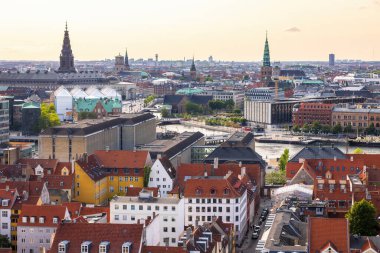 Kurtarıcımız Kilisesi 'nin tepesinden alınan Kopenhag' ın panoramik manzarası sıcak bir akşam gökyüzü altında tarihi çatılar, modern binalar ve şehir simgelerinin bir karışımını gösteriyor..