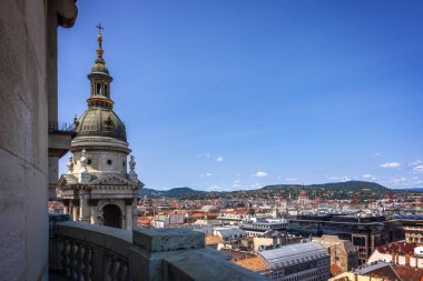Budapeşte 'deki Aziz Stephen Bazilikası' nın yakın görüntüsü, gözlem güvertesinden şehrin çatıları ve uzak tepeleri ile aydınlık bir yaz gökyüzünün altında çekildi..