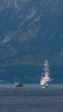 Kotor, Karadağ - 09 Eylül 2025: Beyaz Yelkenli Yat Rüzgarı Karadağ 'ın Kotor Körfezi' ne geri planda dramatik dağlarla giriyor