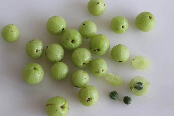 Amla or Indian Gooseberries are small, nutritious fruits produced from gooseberry tree. It has culinary and herbal medicine uses. Shot on white background along with split gooseberry and its seeds