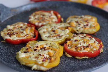 Cheesy vegetarian egg ring. Easy and healthy breakfast. Omelette prepared in bell pepper rings with cheese oregano and chili flakes toppings. Shot on a white background with veg rings on a frying pan