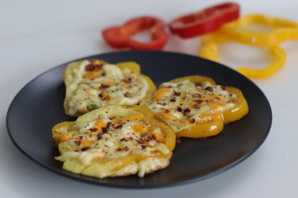 Cheesy vegetarian egg ring. Easy and healthy breakfast. Omelette prepared in bell pepper rings with cheese oregano and chili flakes toppings. Shot on a white background with veg rings on a frying pan