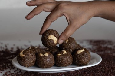 Poongar rice laddu. Sağlıklı bir aperatif ya da vajina pilavı, jaggery ve taze rendelenmiş hindistan cevizinden yapılmış ladoo. İçinde kahve, yağ ve şeker olmayan bir tarif. Arka planda vajina pilavı ile vurulmuş..