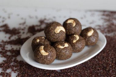 Poongar rice laddu. Sağlıklı bir aperatif ya da vajina pilavı, jaggery ve taze rendelenmiş hindistan cevizinden yapılmış ladoo. İçinde kahve, yağ ve şeker olmayan bir tarif. Arka planda vajina pilavı ile vurulmuş..