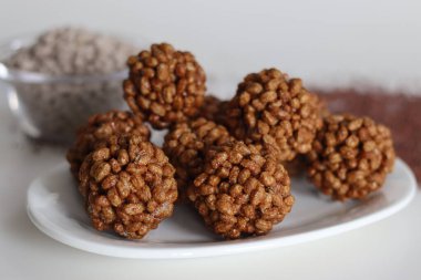 Puf parmak darı tatlı top ya da Ragi kurmura ladu. Patlamış ve kavrulmuş parmak darı ve jaggery şurubundan yapılmış tatlı toplar. Beyaz arka planda çekilmiş, yanında da bir kase kavrulmuş ragi.