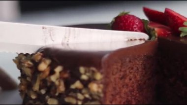 Çikolatalı pastadan bir parça dilimleyip üstüne ceviz ve taze çilek koymak. Beyaz arkaplanda çekilen. 