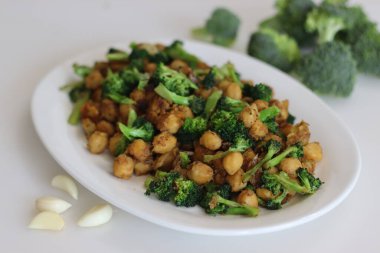 Nohut brokoli kızartması. Sarımsak ve brokoliler nohutla kızartılmış. Sağlıklı bitki temelli protein içeren bir vejetaryen yiyeceği. Beyaz arkaplanda çekilen