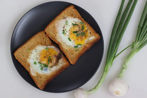 Bulls eye on bread toast. Egg fried in a hole made in the centre of toast. A quick breakfast option, also called bulls eye toast or egg in the basket or egg in a hole. Shot along with spring onions.