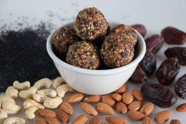 Şekersiz hurma ve fındıklı ladoo. Hurma, badem, ceviz ve susam tohumlarından yapılmış ladoo şeklinde sağlıklı ve protein açısından zengin enerji topları. Beyaz arkaplanda çekilen