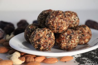Şekersiz hurma ve fındıklı ladoo. Hurma, badem, ceviz ve susam tohumlarından yapılmış ladoo şeklinde sağlıklı ve protein açısından zengin enerji topları. Beyaz arkaplanda çekilen