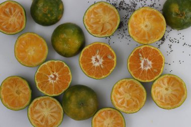 Yarısı dilimlenmiş Nagpur portakalları ve bir kase siyah chia çekirdeği. Nagpur turuncusu, içi turuncu ve dışı yeşil renkli..