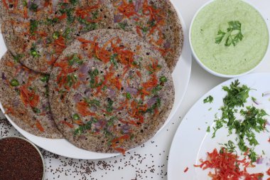 Parmak darı ya da Ragi Uthappam. Mayalanmış parmak darı ve mercimekten yapılmış sağlıklı bir gözleme. Üstünde soğan, havuç, kişniş ve yeşil biber var. Kişniş turşusuyla servis edilir..