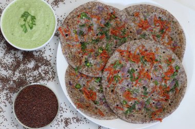 Parmak darı ya da Ragi Uthappam. Mayalanmış parmak darı ve mercimekten yapılmış sağlıklı bir gözleme. Üstünde soğan, havuç, kişniş ve yeşil biber var. Kişniş turşusuyla servis edilir..