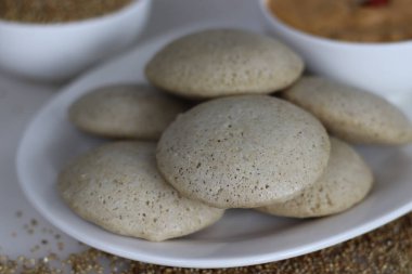 Bajra aylak aylak. Fermente edilmiş siyah mercimek ve parlatılmamış inci darı hamuru tarafından yapılan buğulanmış lezzetli pirinç keki. Arka planda Bajra ile birlikte beyaz arkaplanda çekilmiştir.