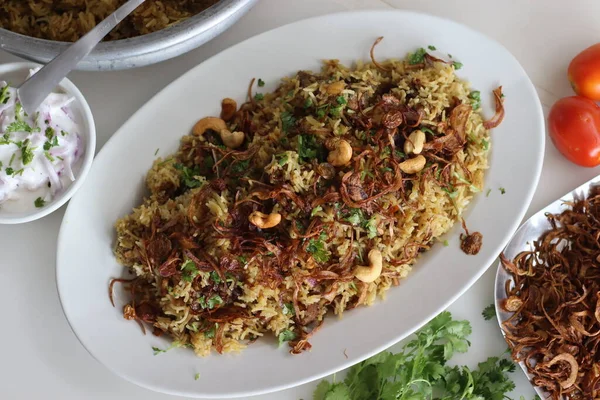Mutton Biryani prepared with spices layered between mildly spiced ghee rice with a generous sprinkle of caramelized onions and Mutton marinated in yogurt. Served with yogurt onion salad