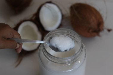 Buzdolabından alınmış cam bir şişede donmuş hindistan cevizi yağı. Hindistan cevizi yağı, kışın ya da soğuktan donarak eriyen bir yağ türüdür.