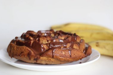 Üzerine çikolata sosu sürülmüş gül şeklinde tam buğday ekmekli kek. Sağlıklı çay zamanı keki, kepekli un ve olgun muz püresi. Küf gibi bir çiçekte pişirilmiş. Olgun muz suyuyla vuruldu..