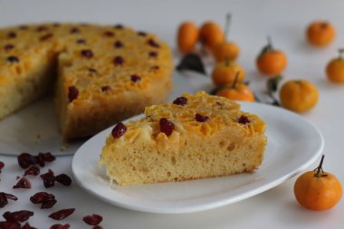 Bir dilim portakallı kek. Ev yapımı portakallı baş aşağı pasta, üstünde bebek portakalı veya mandalina dilimleri ve dekorasyon için kurutulmuş yaban mersini. Beyaz arkaplanda çekilen