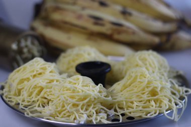 Ethakka idiyappam boş kalıbın içinde servis edilir. Buğulanmış muz ile karıştırılmış pirinç unundan yapılan ip sıçrayıcıları veya idibulpam. Geleneksel idiyappam presi ve olgun muz ile vurulmuş.