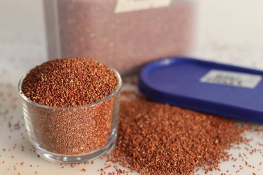 Parmak darı taneleri depolama kabında muhafaza edilir ve ağzına kadar dolu cam kase, zengin renk ve dokularla dolu haşhaş tohumlarına benzeyen küçük siyah taneleri vurgular..