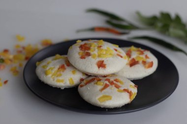 Doldurulmuş dolmalık biber. Renkli ve iştah açıcı bir Güney Hindistan kahvaltısı. Buharda pişirilmiş pirinç keki mayalanmış siyah mercimek ve dolmalık biberli pilav ile yapılır.