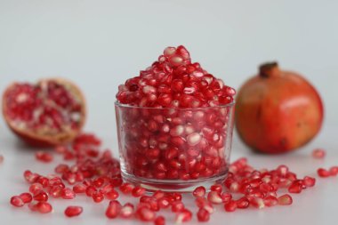 Canlı nar meyvesi ve cam bir kasede parlayan kemer gibi kırmızı inci. Tazelik ve sulu bir cazibe sergiliyor. Beyaz arkaplanda çekilen.