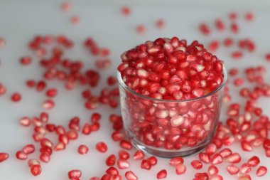 Canlı nar meyvesi ve cam bir kasede parlayan kemer gibi kırmızı inci. Tazelik ve sulu bir cazibe sergiliyor. Beyaz arkaplanda çekilen.