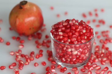 Canlı nar meyvesi ve cam bir kasede parlayan kemer gibi kırmızı inci. Tazelik ve sulu bir cazibe sergiliyor. Beyaz arkaplanda çekilen.