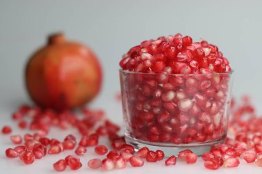 Canlı nar meyvesi ve cam bir kasede parlayan kemer gibi kırmızı inci. Tazelik ve sulu bir cazibe sergiliyor. Beyaz arkaplanda çekilen.