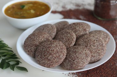 Ragi Idli, sambhar 'la hizmet etti. Parlak parmak darı mayalanmış hamuru ve desenli siyah gramla yapılmış besleyici bir Güney Hindistan zımbası. Gelenek, yiyecek ve sağlığın mükemmel bir karışımı..