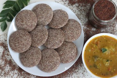 Ragi Idli, sambhar 'la hizmet etti. Parlak parmak darı mayalanmış hamuru ve desenli siyah gramla yapılmış besleyici bir Güney Hindistan zımbası. Gelenek, yiyecek ve sağlığın mükemmel bir karışımı..