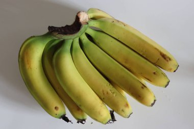 Robusta muzlu. Bir düzine Robusta muzundan oluşan canlı bir küme, olgun ve cömert. Sağlıklı yaşam tarzı, tropikal meyve, organik atıştırmalık ve çiftlik tazeliği kavramları için mükemmel. Beyaz arkaplanda çekilen