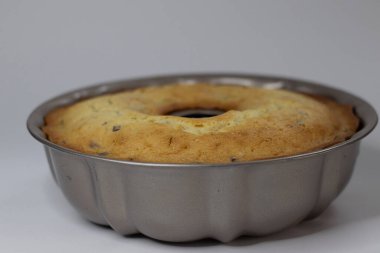 Fırından yeni çıkmış klasik tavanın içinde kızılcık portakallı kek var. Yaban mersinli ve portakallı tereyağlı lezzetli pasta. Beyaz arkaplanda çekilen