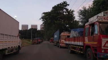 Vikhroli, Mumbai, Hindistan, 3 Haziran 2024: Yolun her iki tarafına park edilmiş ticari araç kuyruğu arasında ilerlemek fabrikadan mal yükleme sıralarını beklemek. Endüstriyel ilerleme ve büyüme işareti