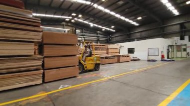 Pune, Hindistan, 21 Haziran 2024: Bir Godrej forklift, bir parçacık tahtasını ustalıkla diğerlerinin üst sıralarına yerleştirdi. Forkliftler ağır yüklerle başa çıkmada önemli bir rol oynar