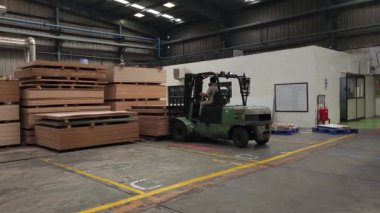 Pune, Hindistan, 21 Haziran 2024: Bir Godrej forklift güvenlik ve güvenliği sağlamak için bir yığın diğer parçacık tahtasından ustalıkla bir palet aldı. Forkliftler ağır yüklerle başa çıkmada önemli bir rol oynar