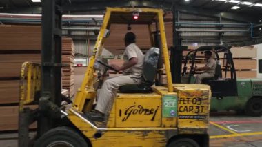 Pune, Hindistan, 21 Haziran 2024: Bir Godrej forklift, bir parçacık tahtasını ustalıkla diğerlerinin üst sıralarına yerleştirdi. Forkliftler ağır yüklerle başa çıkmada önemli bir rol oynar