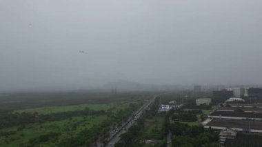Mumbai, Hindistan, 5 Ağustos 2024: Vikhroli 'deki Godrej Kampüsü' nün üzerinden geçen ve Doğu Ekspres Otoyolu ve yerel trende trafiği olan bir uçağı gösteren bir klip, yağmur sırasında üç ulaşım biçimini vurguluyor