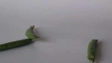 Bir grup taze bezelye kabuğu yere düşüyor, canlı ve organik ürünler sergiliyorlar. Gıda blogları, yemek tarifleri ve sağlıklı yemek içeriği için mükemmel. Taze sebzeleri ve besinleri ön plana çıkarıyor.
