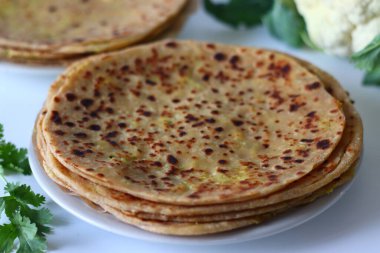 Gobi Paratha, yapraklı taze karnabahar ampulünün yanında servis yaptı. Baharatlı karnabahar dolmasıyla doldurulmuş, sağlıklı ve lezzetli bir yemek için tam buğday unu kullanan klasik bir Hint ekmeği.