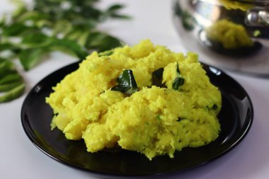 Kaynatılmış ve ezilmiş tapyoka, zerdeçal ile harmanlanmış ve köri yapraklarıyla süslenmiş, canlı ve dokulu bir yemek oluşturuyor. Zengin rengini ve pürüzsüz tutarlılığını vurgulamak için bir açıyla çekilmiş.