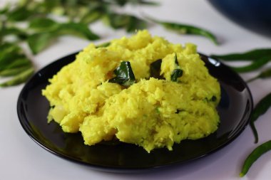 Kaynatılmış ve ezilmiş tapyoka, zerdeçal ile harmanlanmış ve köri yapraklarıyla süslenmiş, canlı ve dokulu bir yemek oluşturuyor. Zengin rengini ve pürüzsüz tutarlılığını vurgulamak için bir açıyla çekilmiş.