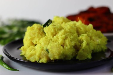 Kaynatılmış ve ezilmiş tapyoka, zerdeçal, yeşil biber ve köri yapraklarıyla karıştırılmış, yanında kızarmış balık. Canlı renklerini ve dokularını vurgulayan bir açıyla yakalandı