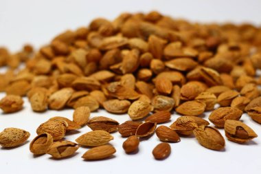 Kabukları beyaz bir yüzeye saçılmış çiğ bademler doğal dokularını ve toprak tonlarını sergiliyor. Sağlıklı yağ, protein ve vitamin içeren bademler kalp sağlığı ve beyin fonksiyonlarını destekler.