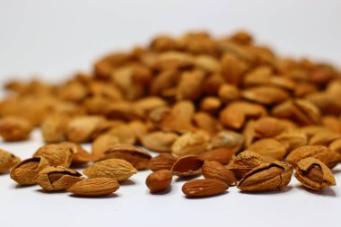 Kabukları beyaz bir yüzeye saçılmış çiğ bademler doğal dokularını ve toprak tonlarını sergiliyor. Sağlıklı yağ, protein ve vitamin içeren bademler kalp sağlığı ve beyin fonksiyonlarını destekler.
